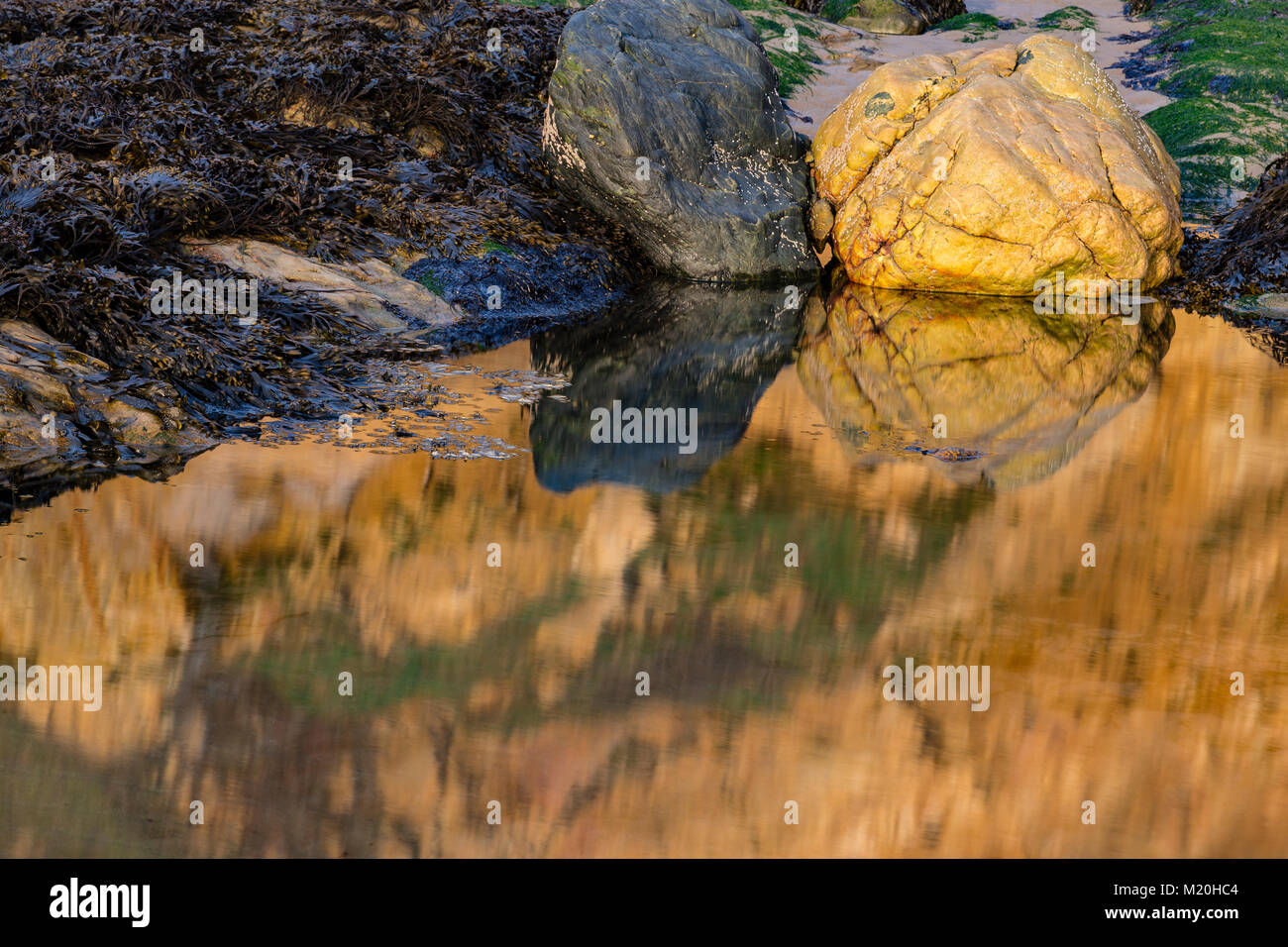 Rocks and cliffs reflecting in a tidal pool on the coast of Anglesey, North Wales Stock Photo