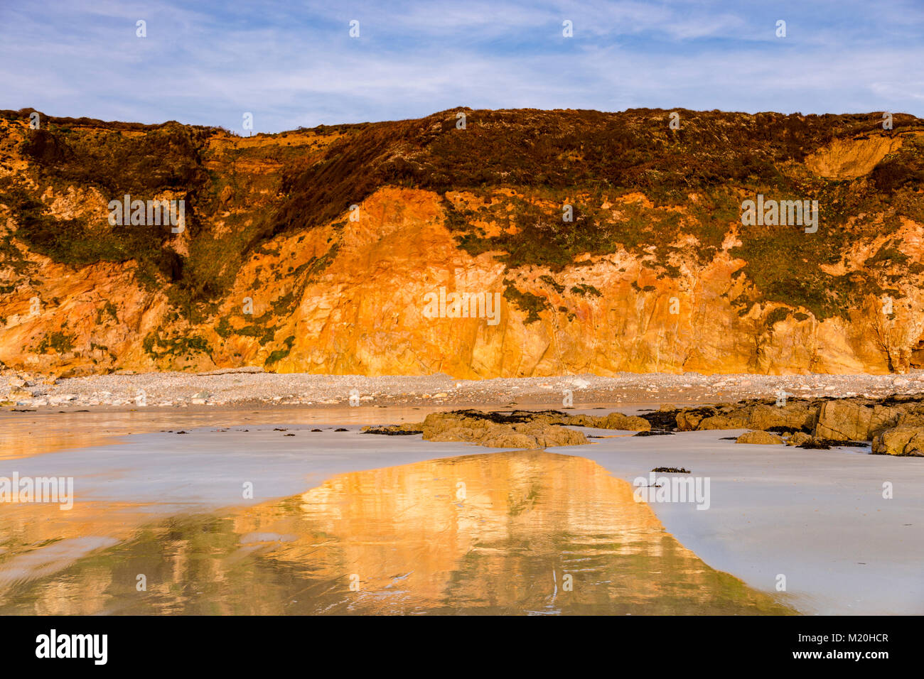 Cliffs reflecting in wet sand on the coast of Anglesey Stock Photo