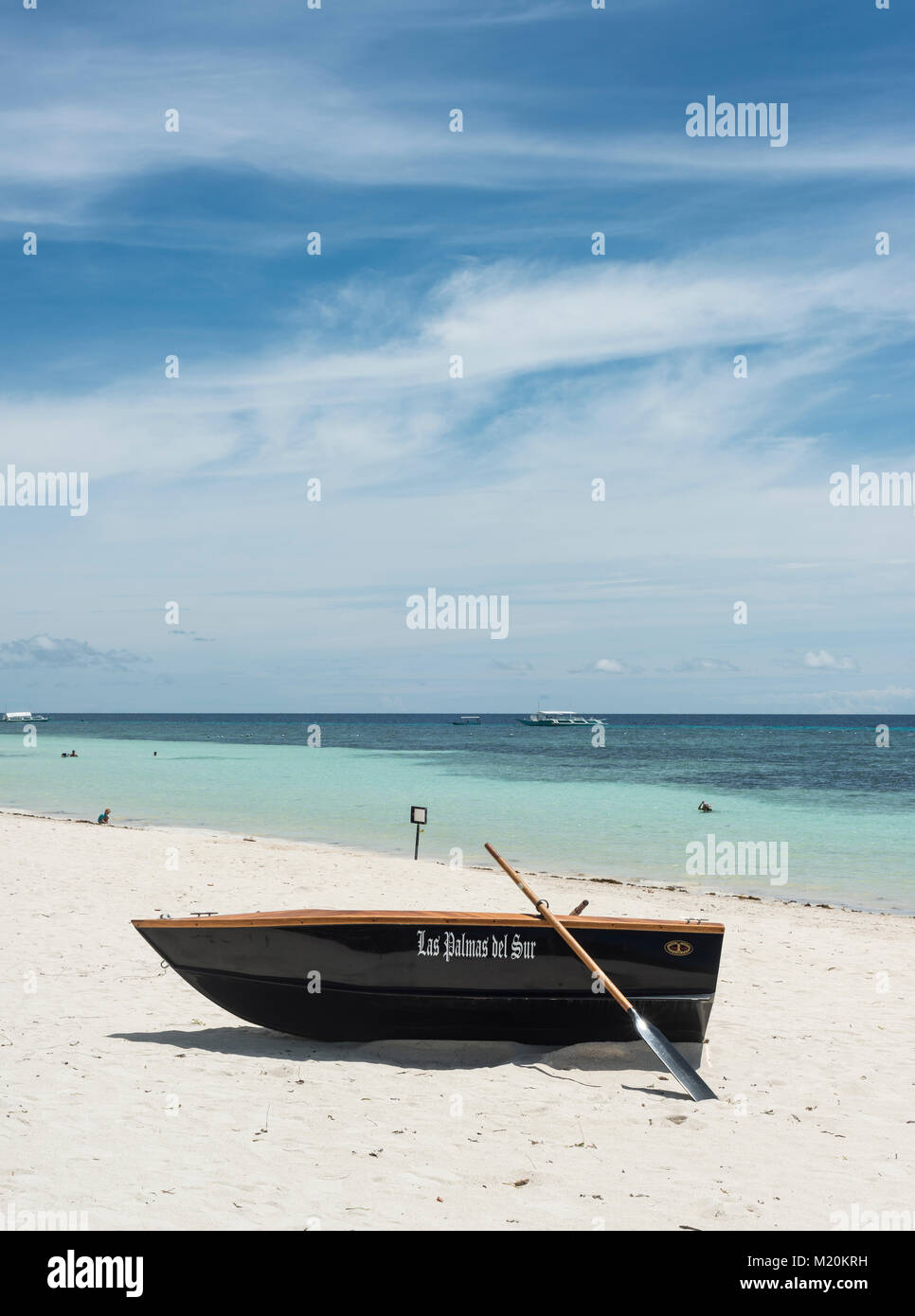 Rowing boat lying on a tropical beach with a calm ocean in the background Stock Photo