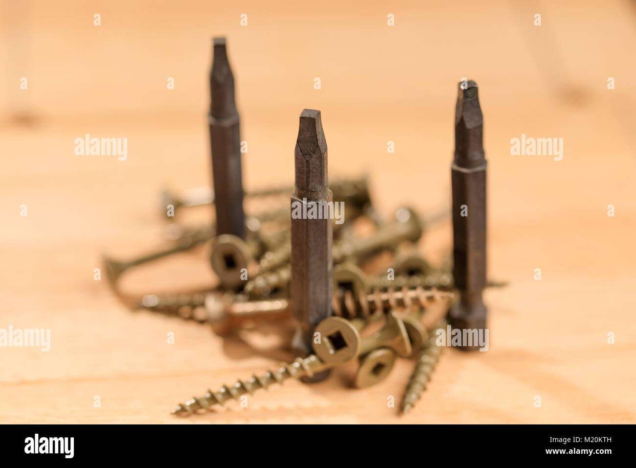 Bits for screwdrivers along with several screws placed on a wooden board. Set of heads for screwdriver (bits). Tools collection of drywall screws. Stock Photo