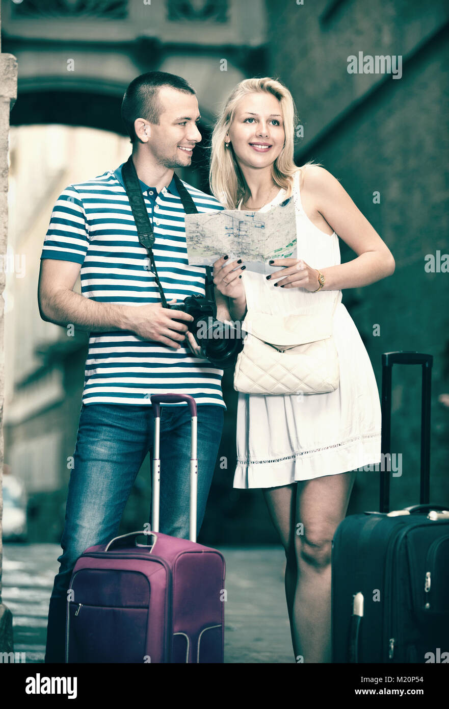 Young cheerful man and positive woman tourists having map and looking ...
