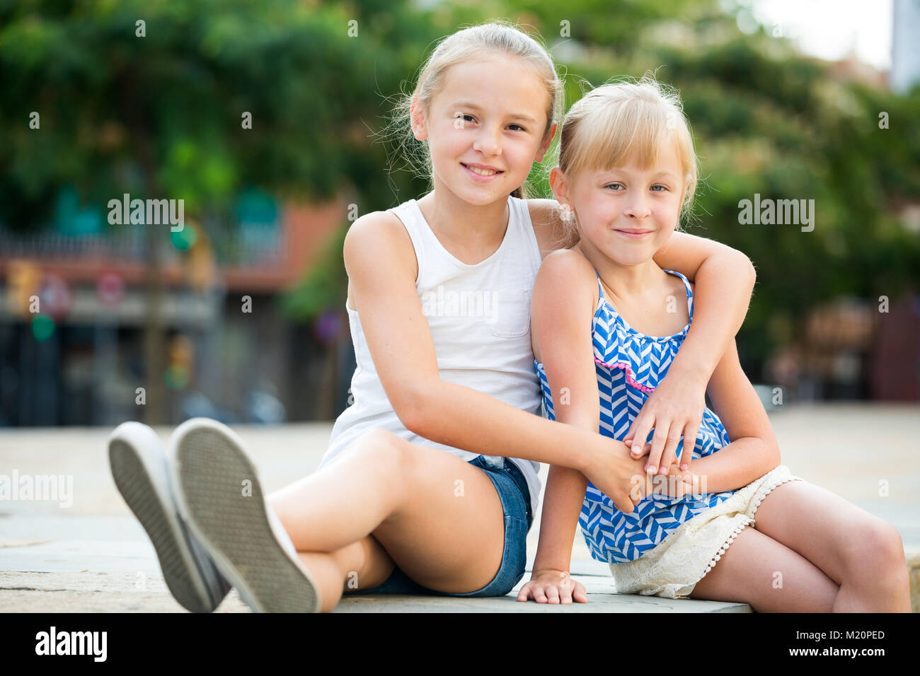 Two smiling little girls embracing each other in summer park Stock ...