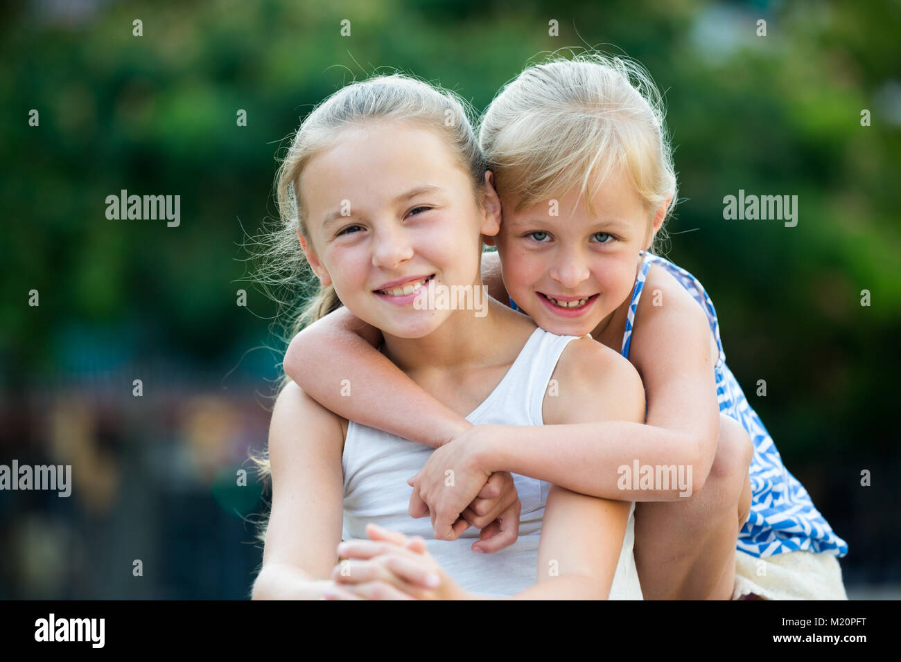 Two smiling little girls embracing each other in summer park Stock ...