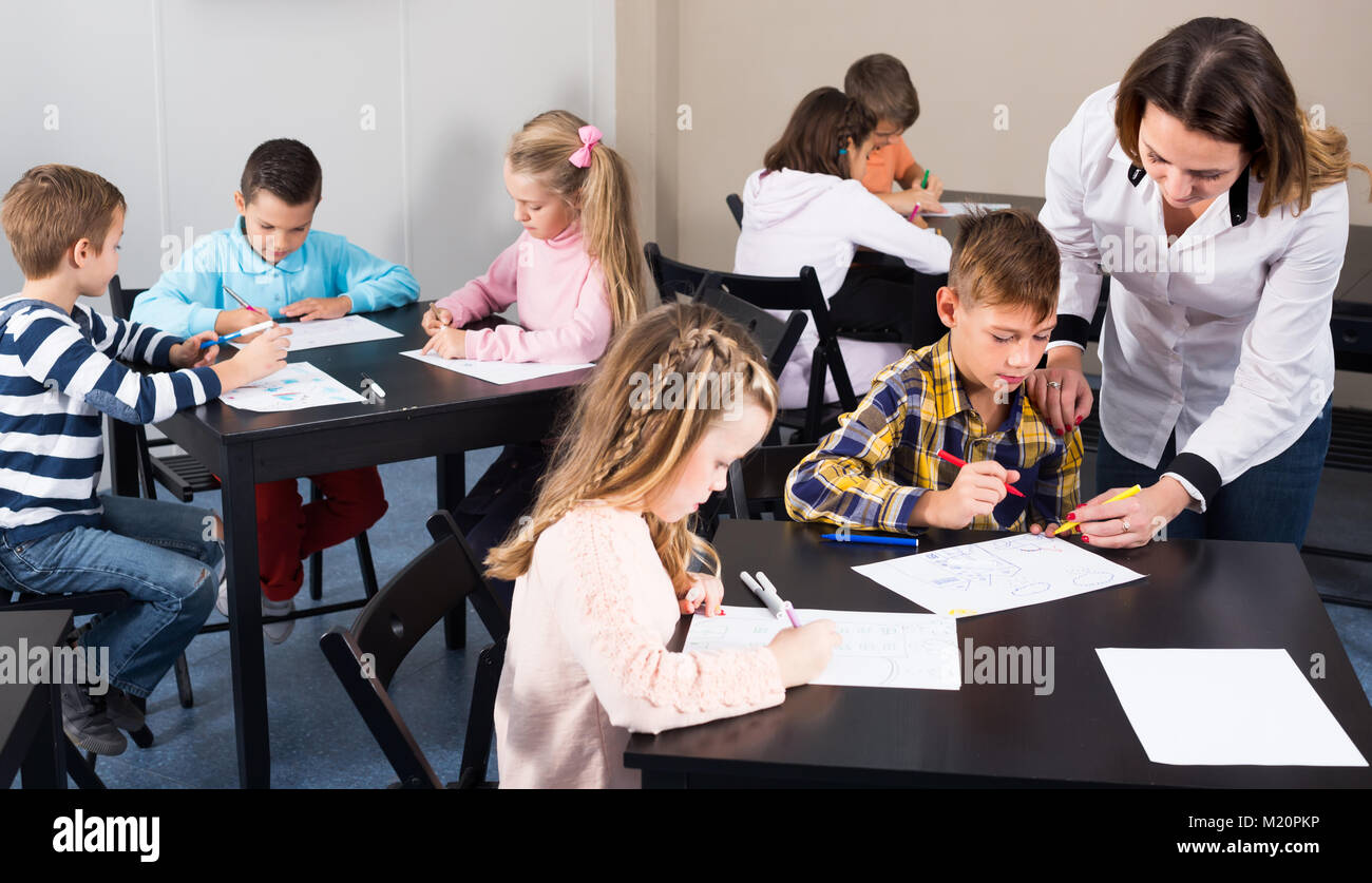 Female teacher and elementary age kids drawing at class Stock Photo - Alamy