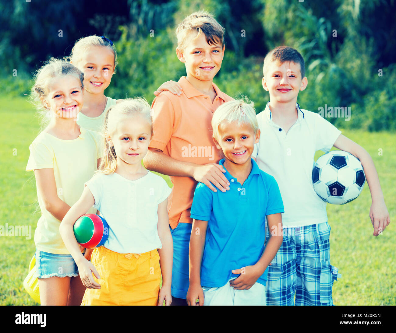 Group of kids in school age standing on green lawn in park Stock Photo ...
