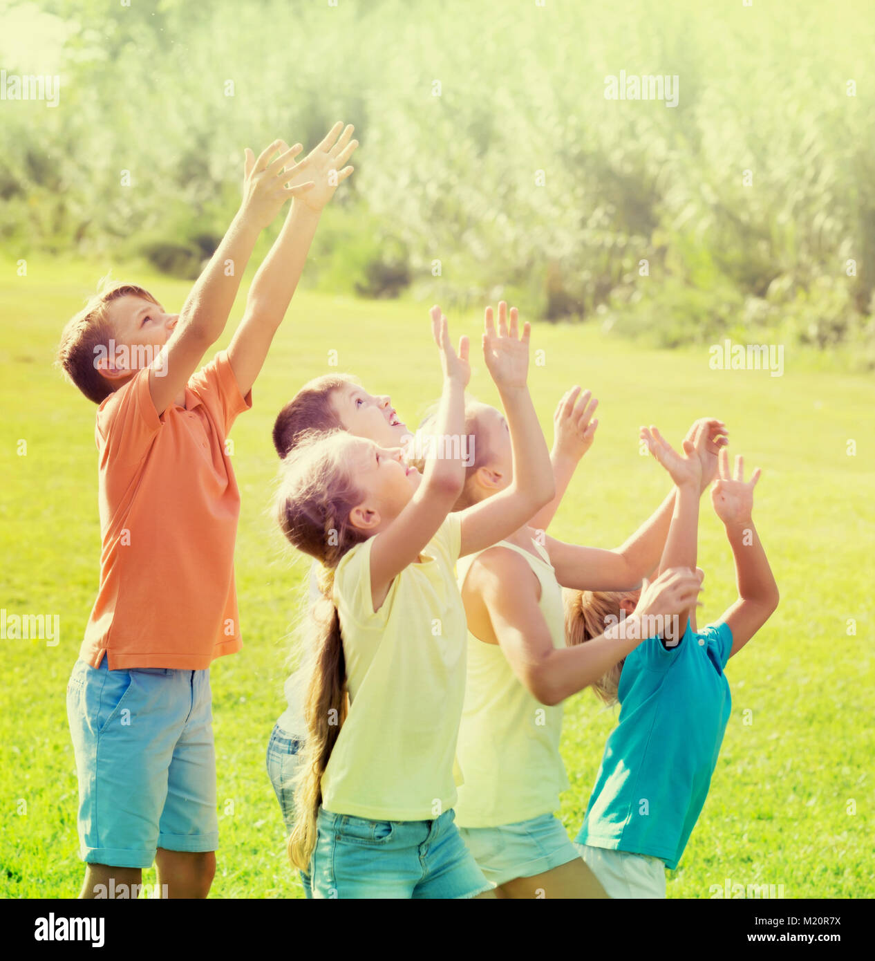 smiling kids in school age jumping together in park on summer Stock ...