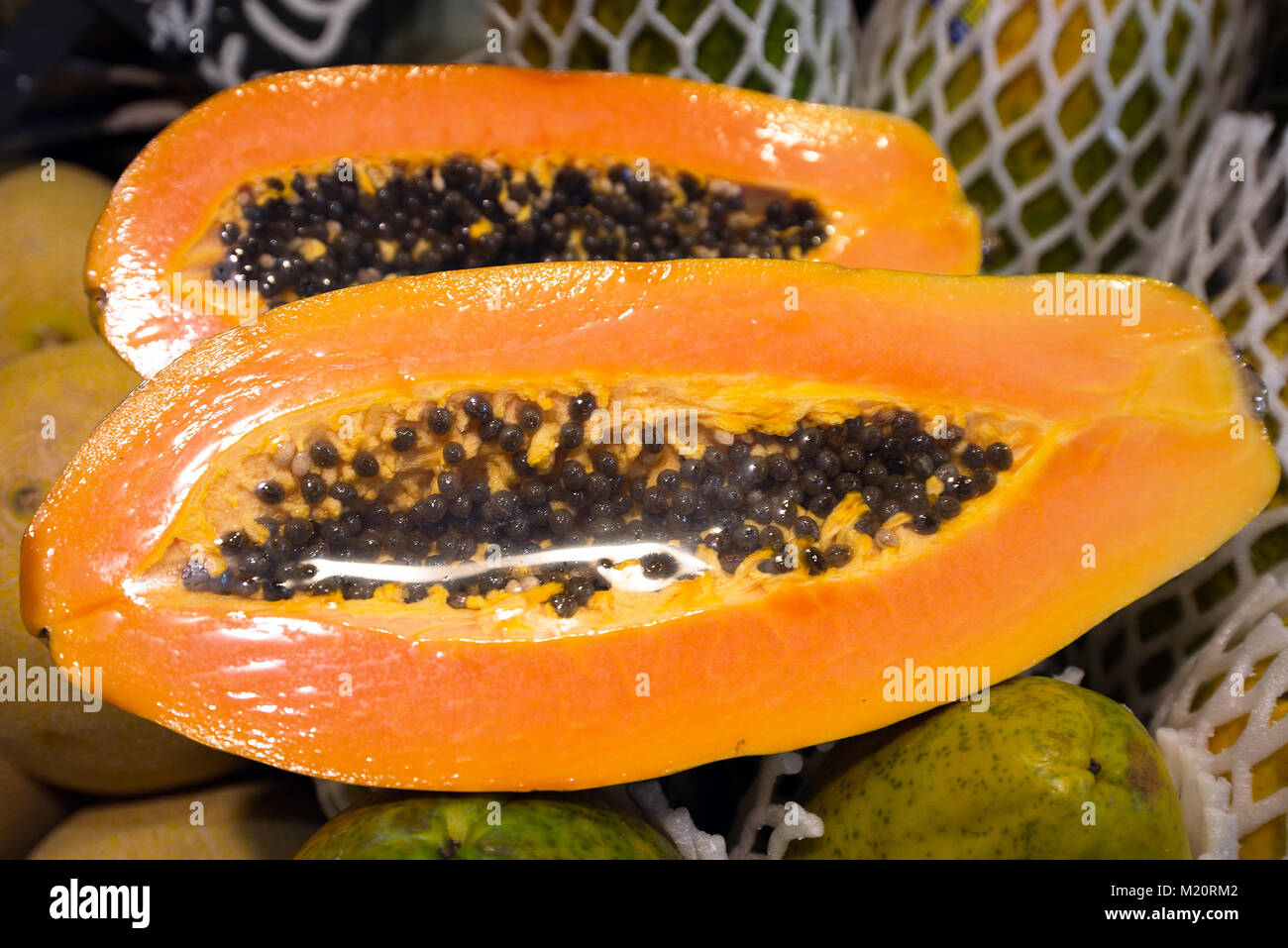 Europe, Spain, Barcelona. The fruit papaya is cut and packaged for sale in the market Stock