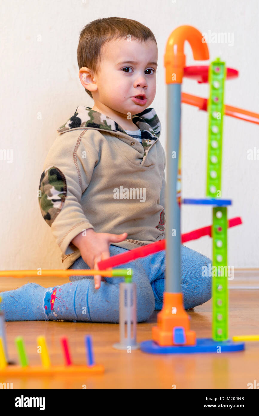 Frustrated baby boy near toys Stock Photo