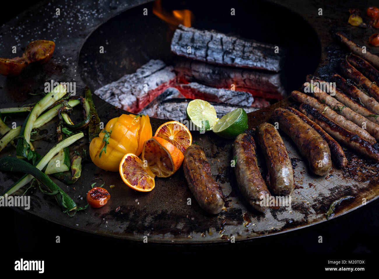 Sausage cooking on a brazier-grill. This new concept - three in one - combines the advantages of cooking with the plancha plus a barbecue and brazier. Stock Photo