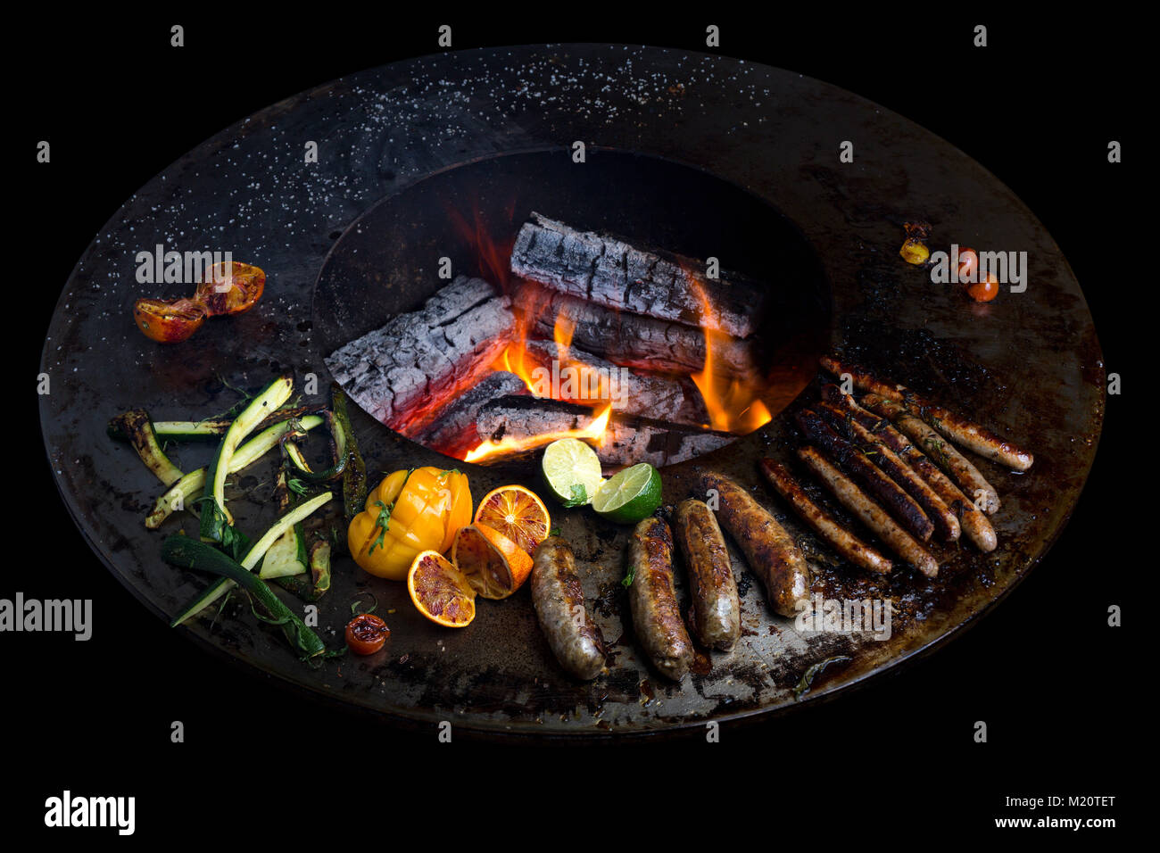 Sausage cooking on a brazier-grill. This new concept - three in one - combines the advantages of cooking with the plancha plus a barbecue and brazier. Stock Photo