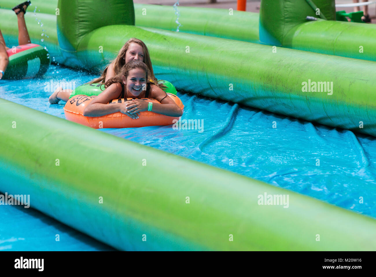 Atlanta, GA, USA - July 15, 2017:  Teenage girls laugh as they travel down a giant slip-and-slide at the Slide The City event in Atlanta, GA. Stock Photo