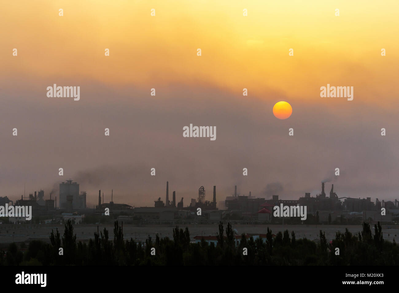 Sun rising through the polluted air in an industrial town in Gansu province, western China. Stock Photo