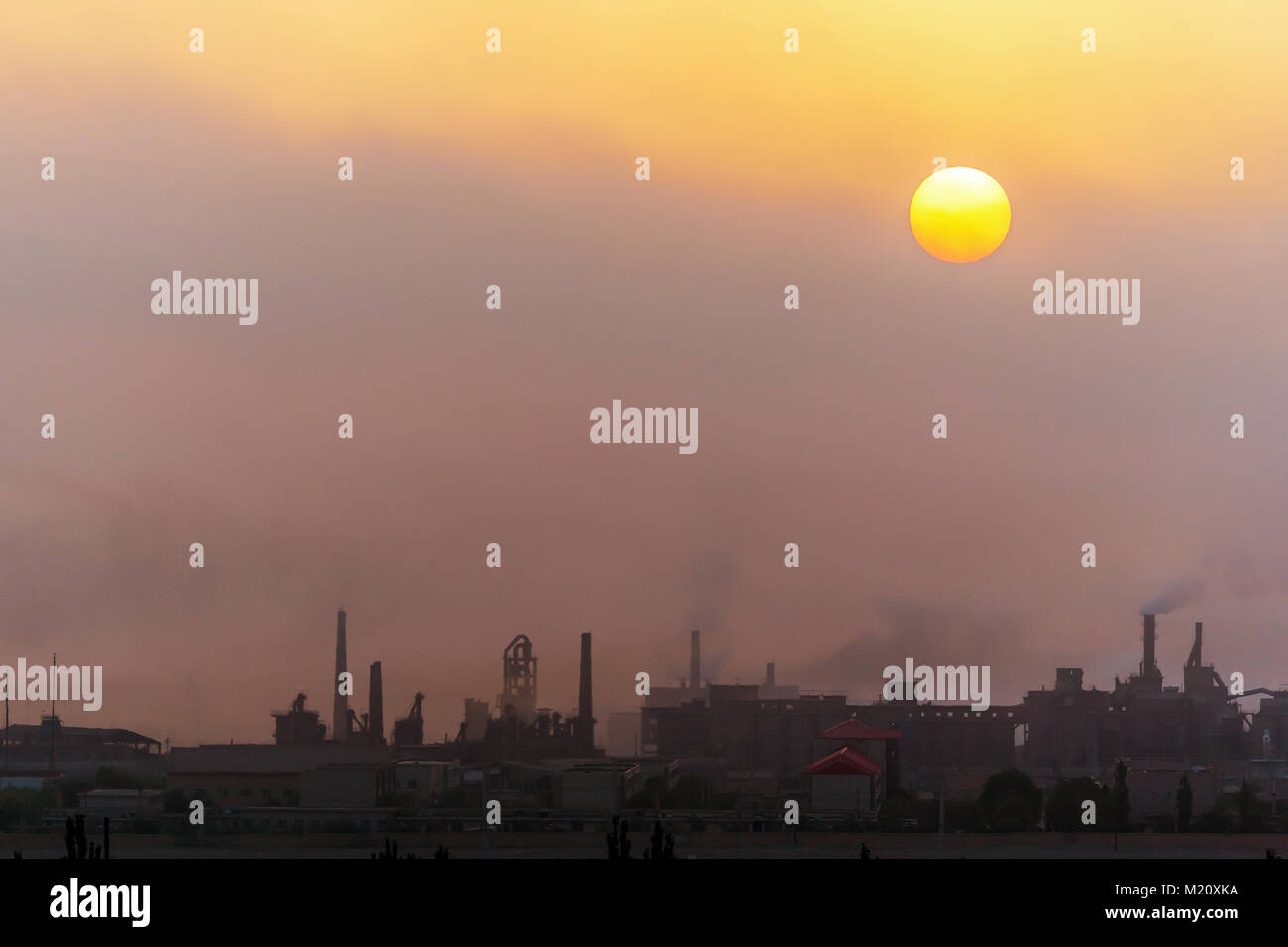 Sun rising through the polluted air in an industrial town in Gansu province, western China. Stock Photo
