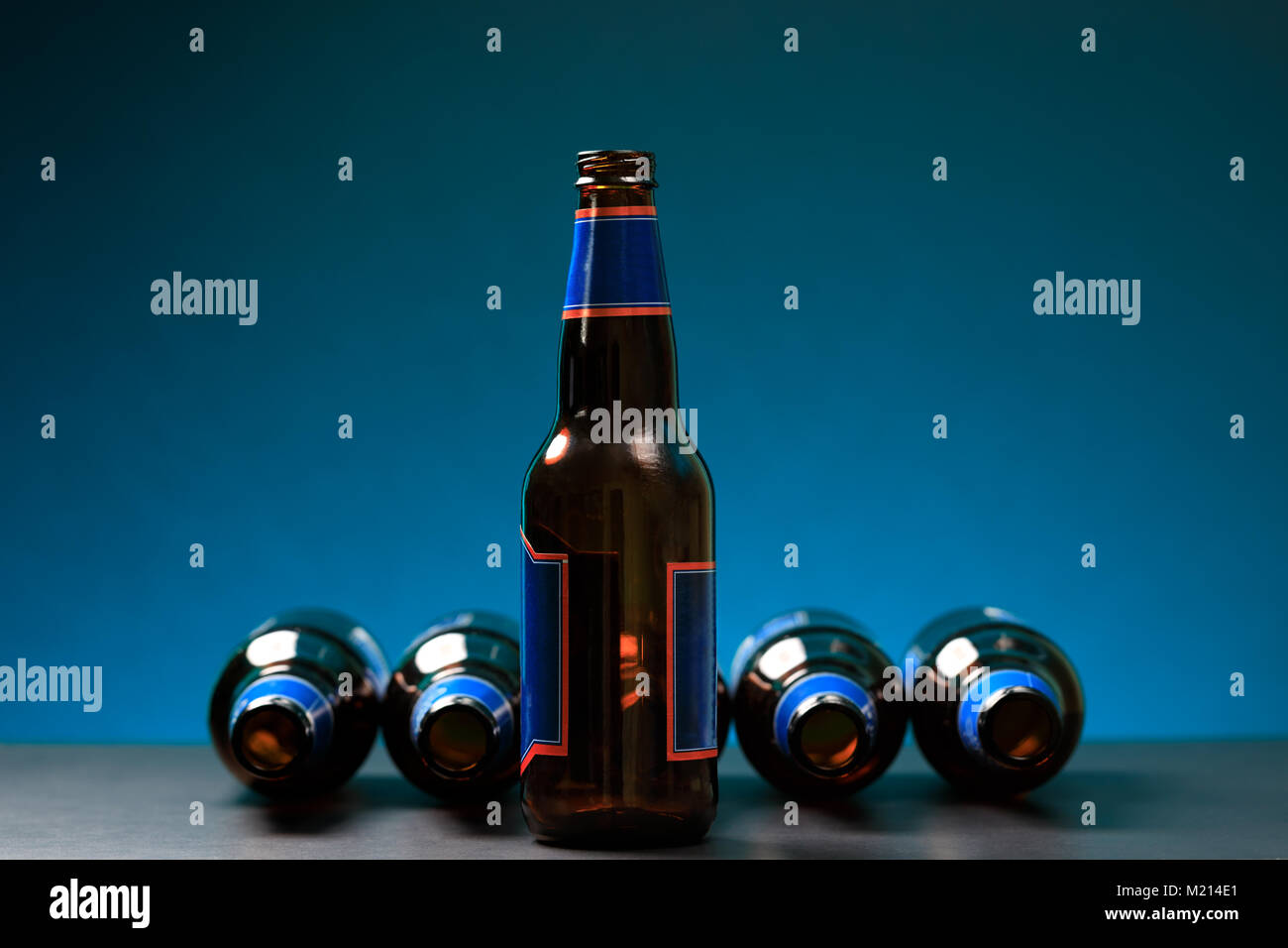 Empty bottle in standing position with other bottles lying down. Glass