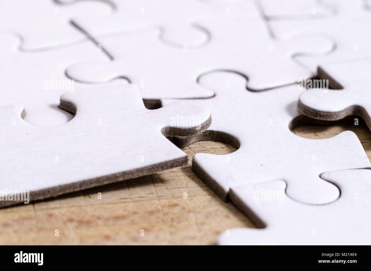 close up of white jigsaw/puzzle with a row in wrong position, over  wooden table background, symbol of problem solving and new vision Stock Photo