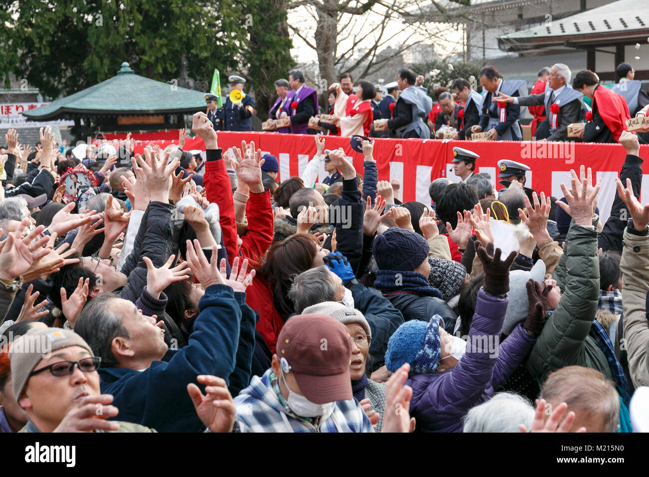 People try to catch soybeans bags during the Setsubun festival at