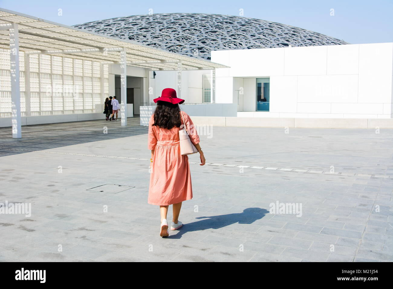 ABU DHABI, UNITED ARAB EMIRATES - JANUARY 26, 2018: Female tourist entering Louvre museum in Abu Dhabi on a sunny day. Louvre is a new museum in Unite Stock Photo