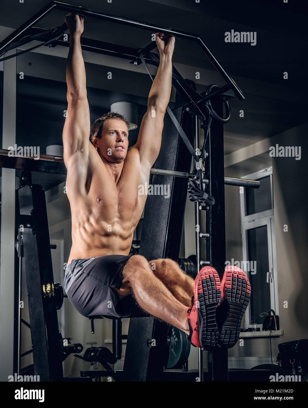 Man Doing Pull-up Bar Abdominal Exercise in Gym Stock Image