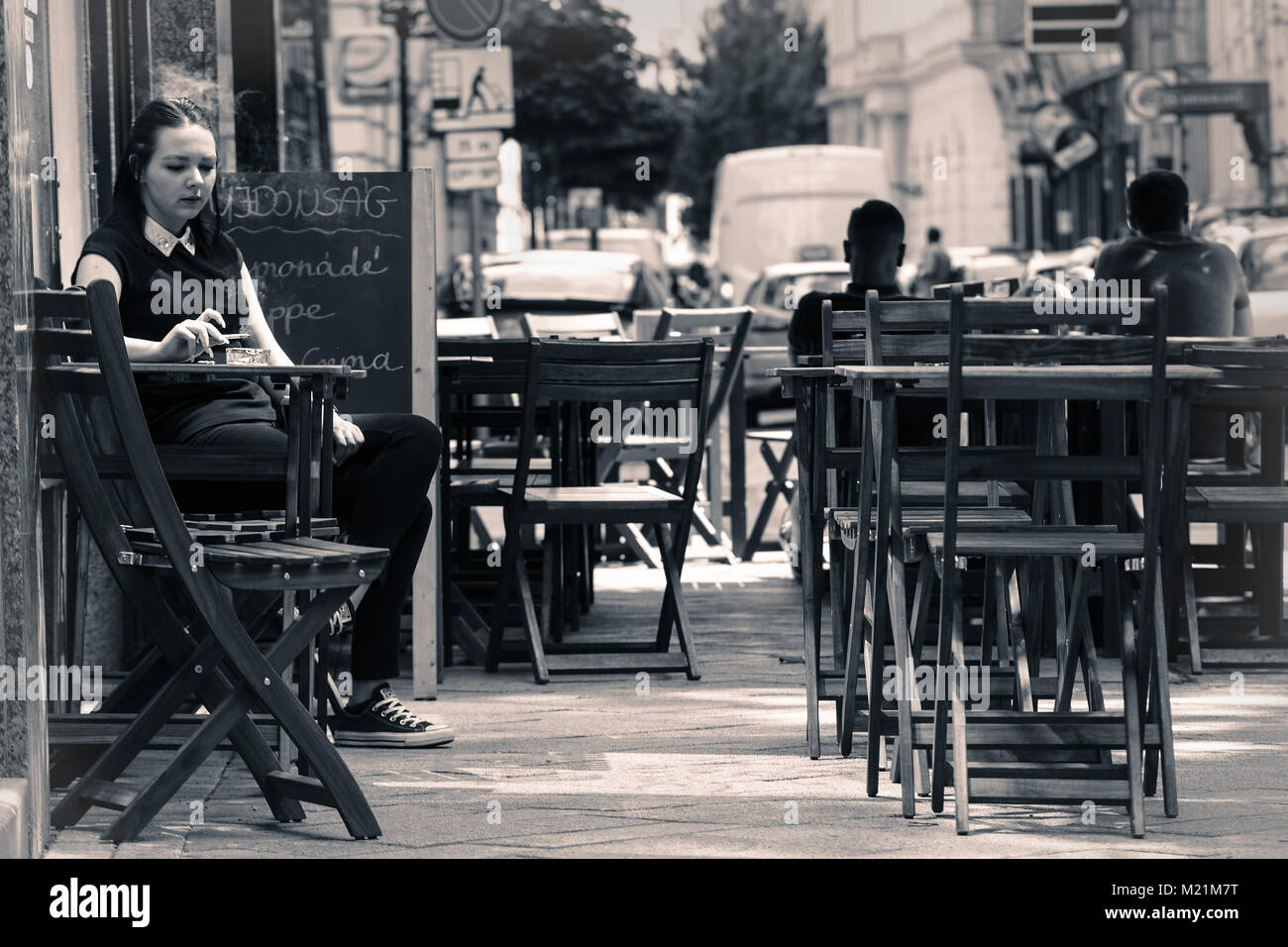 Lonely girl sitting and smoking in retro style street cafe Stock Photo