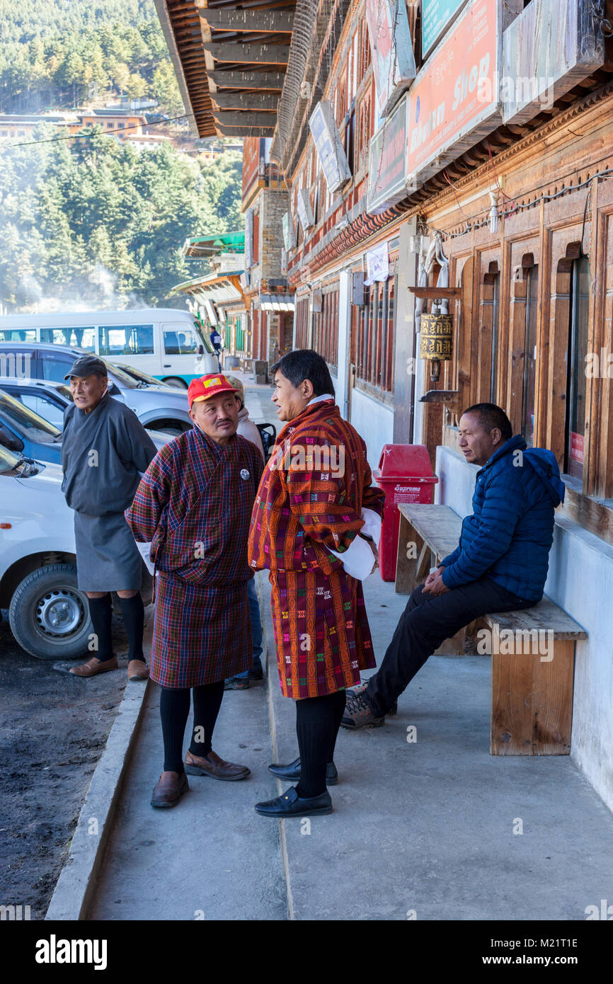 Jakar, Bumthang, Bhutan.  Men Talking on Jakar's Main Street, Wearing Traditional Gho Clothing. Stock Photo