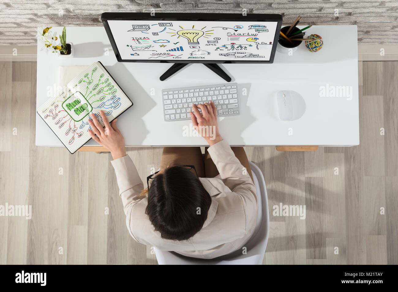 A Businesswoman Planning Start Up Plan On Computer With Mind Map Chart On Notebook Stock Photo