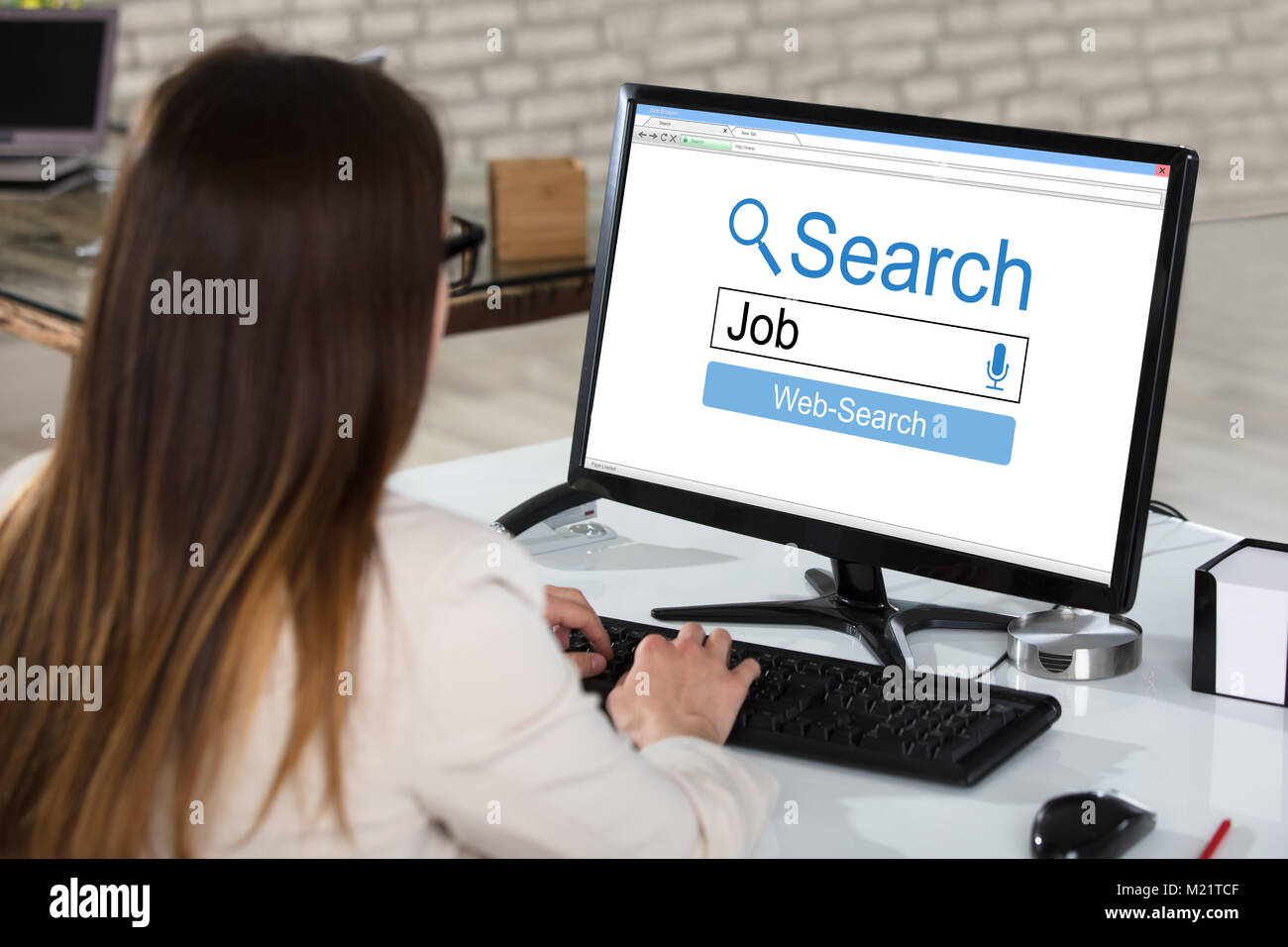 Rear View Of A Businesswoman Searching Online Job On Computer In Office Stock Photo