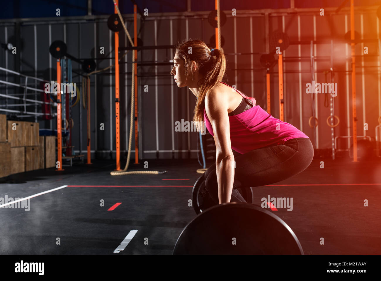 Athletic girl works out at the gym with a barbell Stock Photo