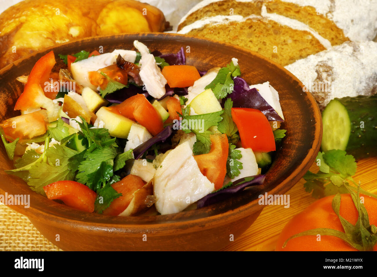 Healthy food. Ceramic bowl with salad with fresh vegetables and chicken. Rural kitchen table. Stock Photo