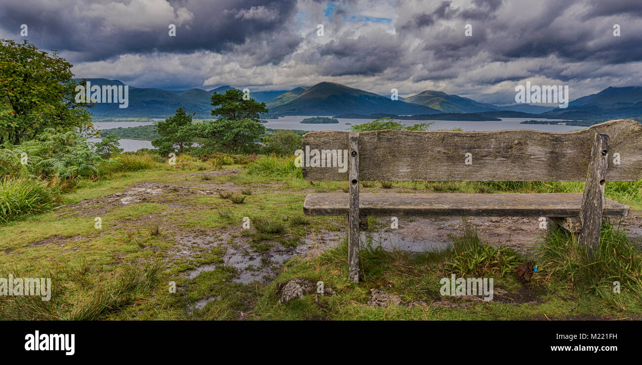 Bench at the viewpoint on top of Tom Na Nighaenan, Inchcailloch, Loch Lomond, looking north west up the loch towards the Arrochar Alps. Stock Photo