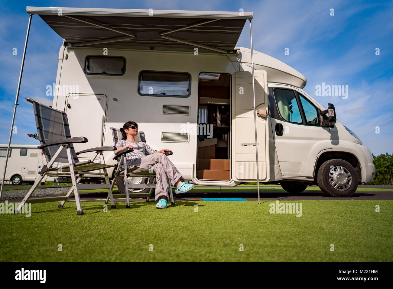 Woman resting near motorhomes in nature. Family vacation travel, holiday trip in motorhome RV, Caravan car Vacation. Stock Photo