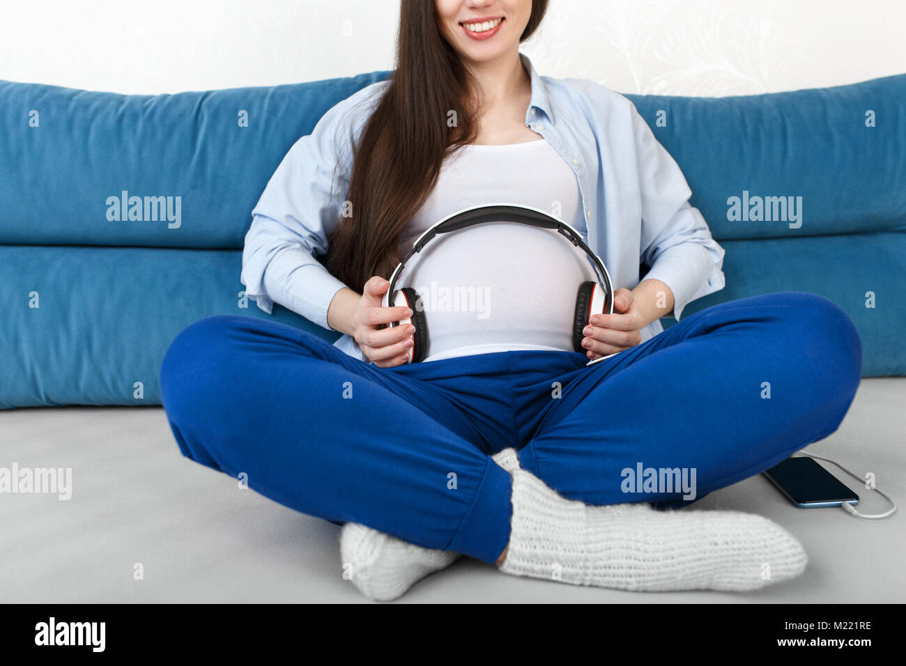 closeup pregnant woman holding headphones on belly Stock Photo