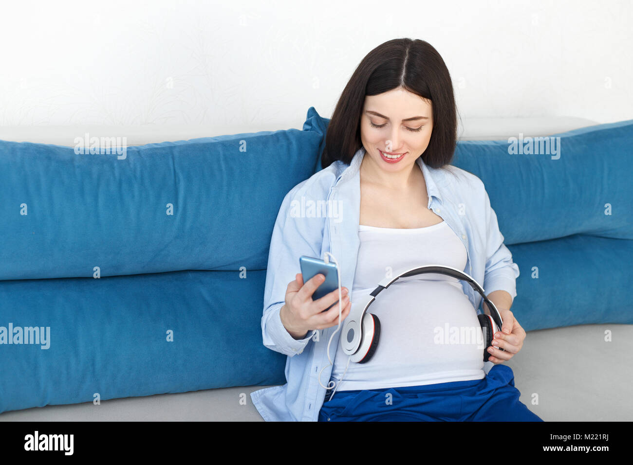 pregnant woman holding headphones on her belly Stock Photo