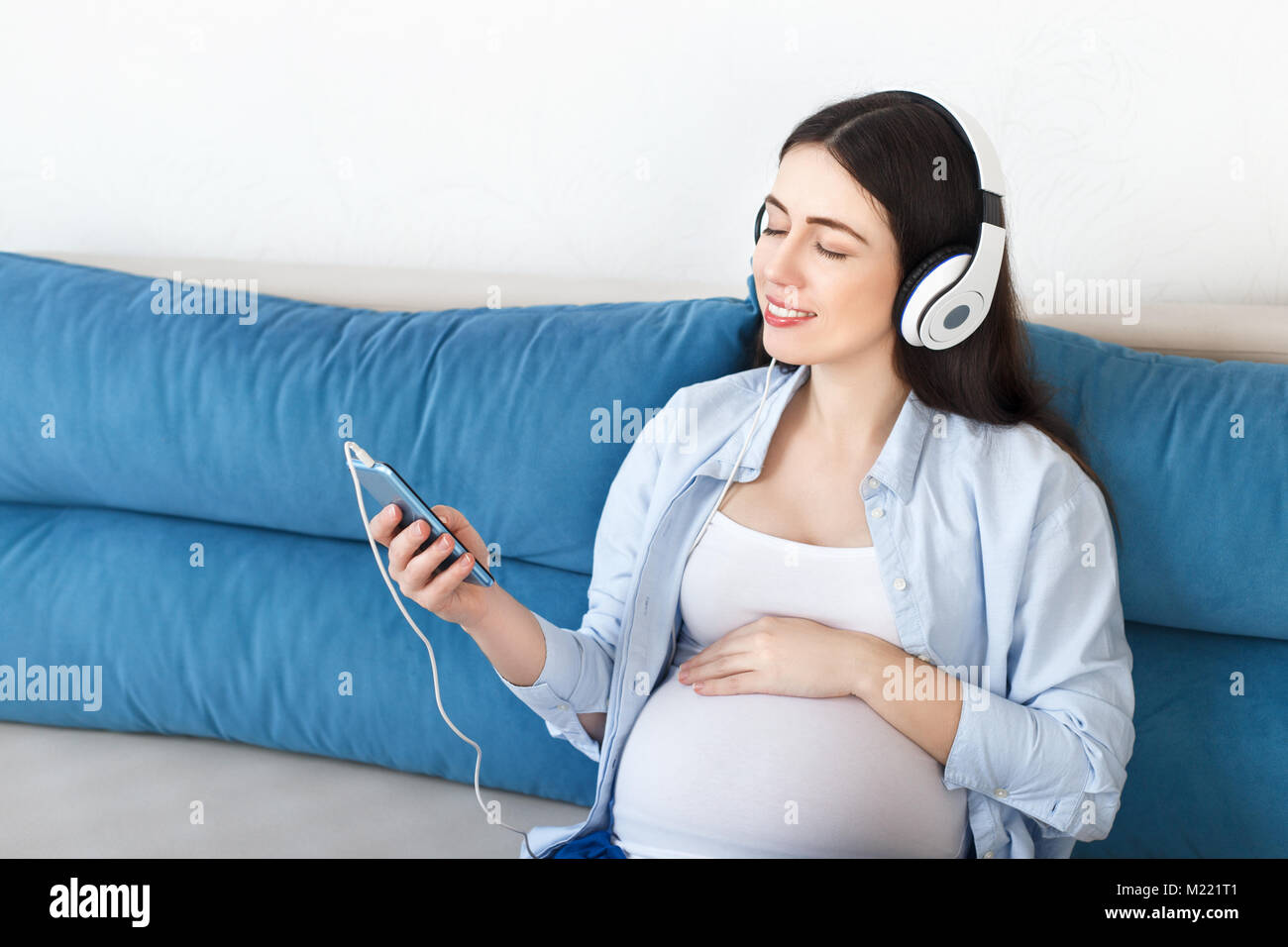 pregnant woman listening music in headphones Stock Photo