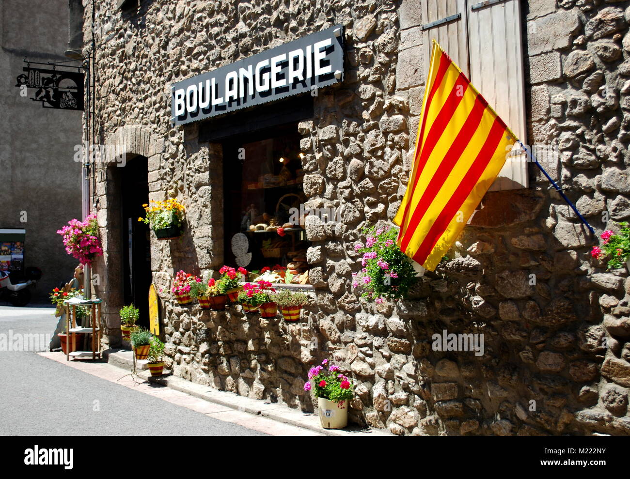 The Catalonian flag hangs outside a bakery on a pretty street in the pretty walled town of Villfranche de Conflent in the south of France. This mediev Stock Photo