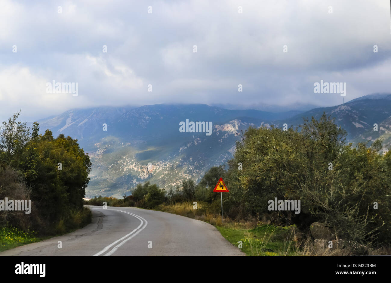 Hairpin curve on two laned road high in mountains that are shouded in ...