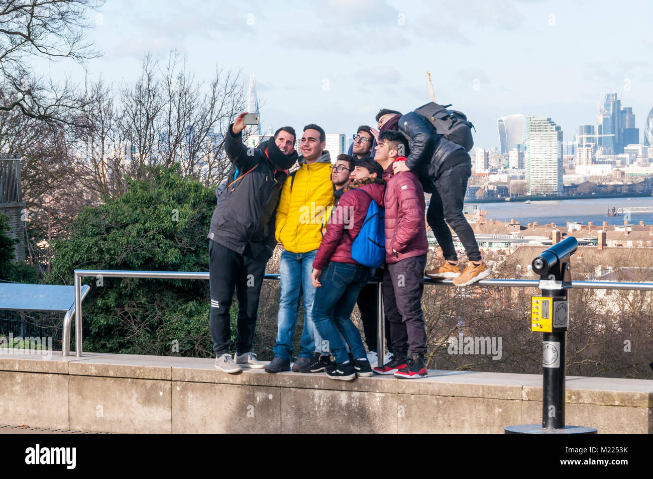 A group of friends taking a selfie at Greenwich in front of the view across the River Thames to the Isle of Dogs, Stock Photo