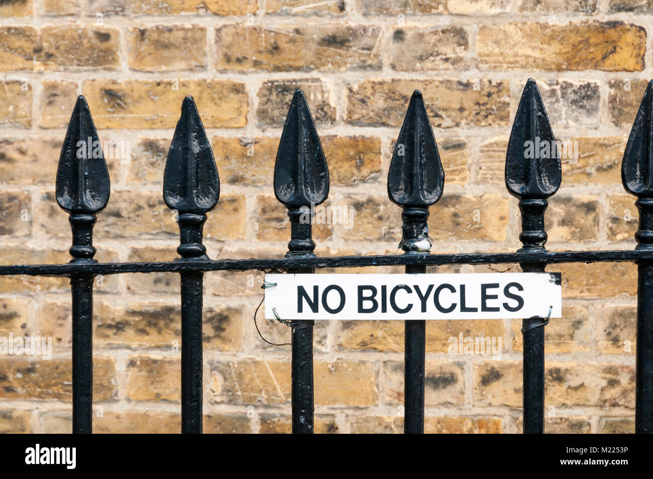 A No Bicycles sign fixed to a set of traditional iron railings. Stock Photo