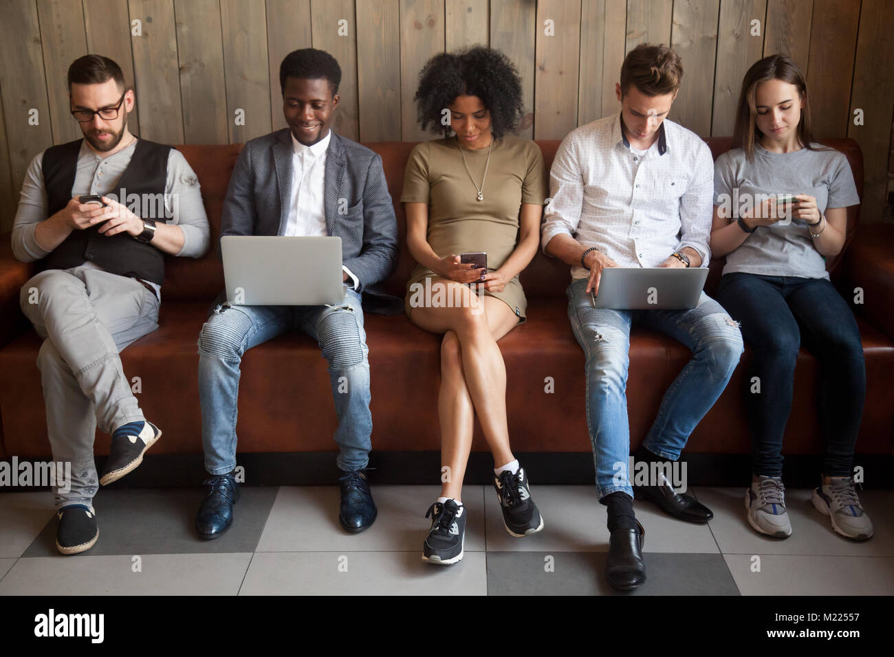 Multicultural young people using laptops and smartphones sitting Stock ...