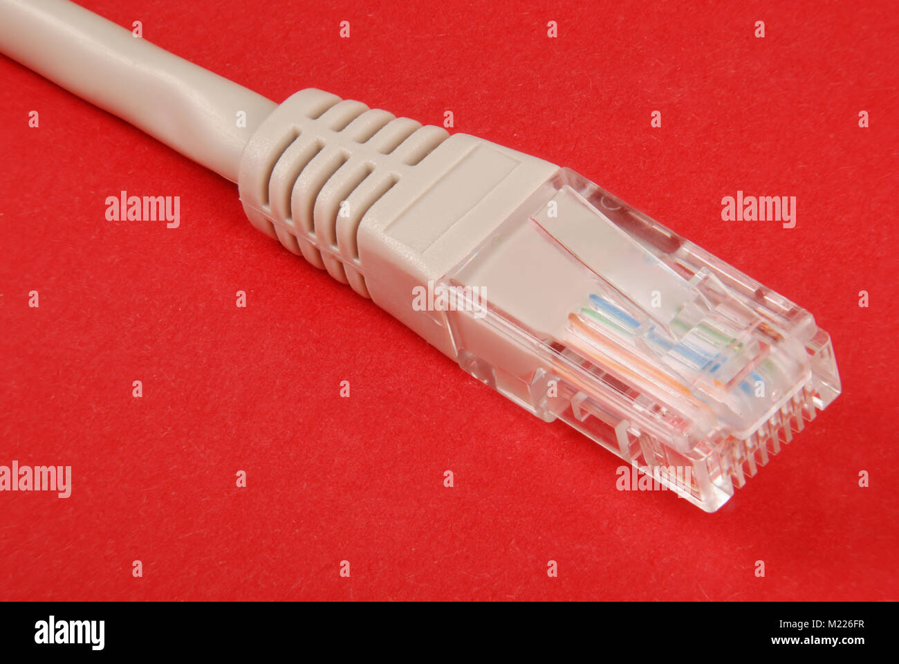 Lan cable and connector RJ45, isolated on red background. Stock Photo