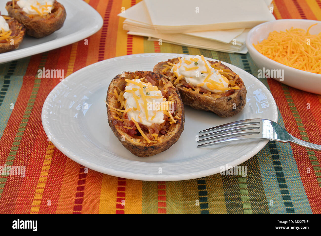 Rustic baked potato skins stuffed with bacon and cheese and topped with sour cream Stock Photo