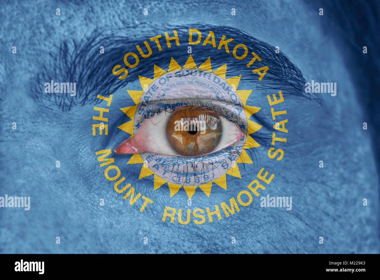 Human face and eye painted with US state flag of South Dakota Stock Photo