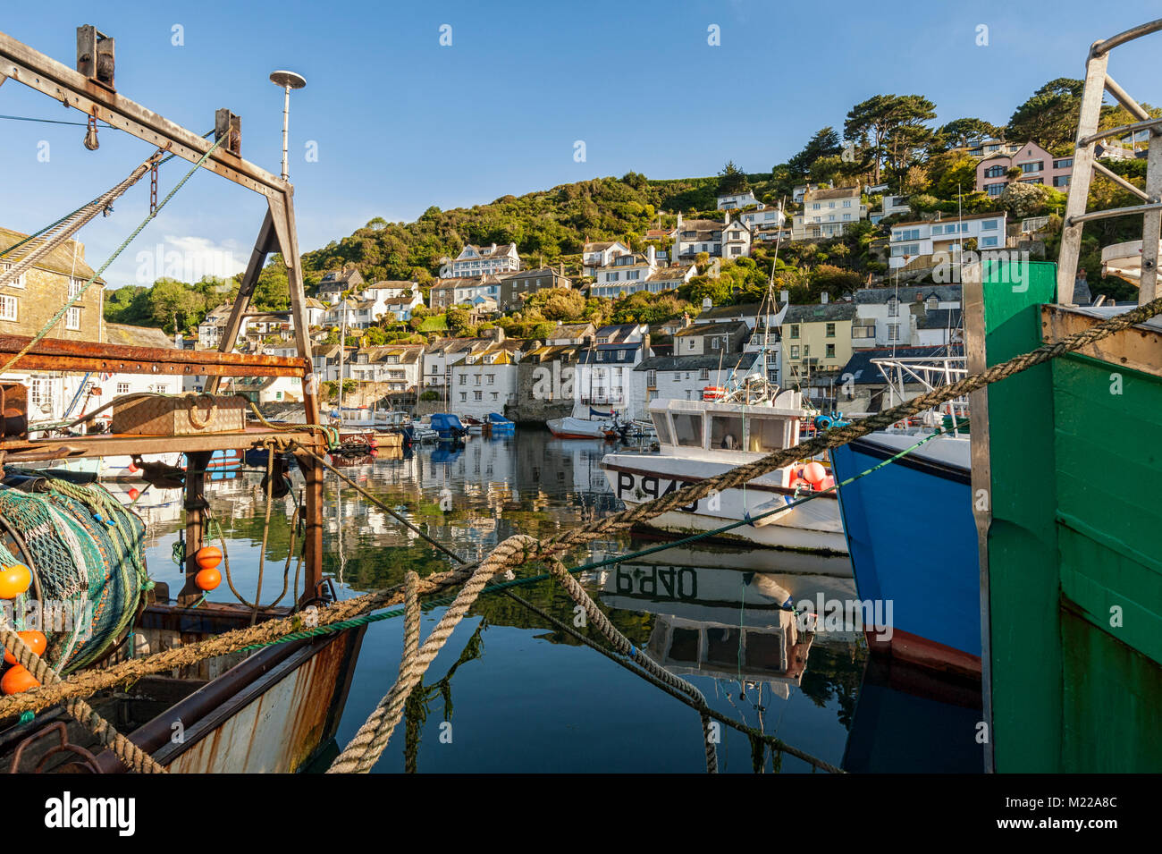 POLPERRO, CORNWALL - JUNE 07, 2009:  Fishing trawlers moored in the pretty Harbour with village seen on the hill behind Stock Photo
