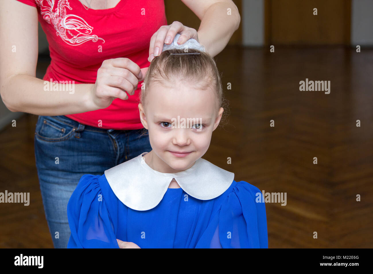 woman makes a girl a hairstyle for a performance Stock Photo
