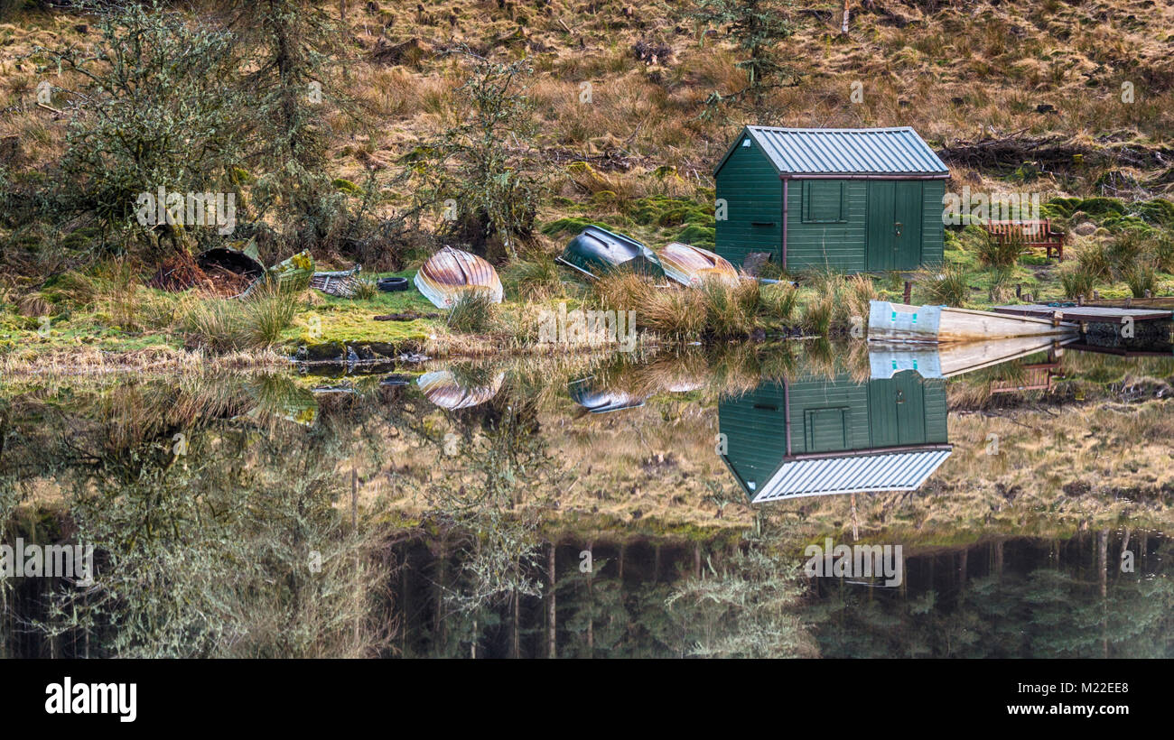 The Boathouse reflected in Allt a' Chip Dhuibh Lochan in the hills south of Loch Venachar, in the Trossachs, in the Scottish Highlands Stock Photo
