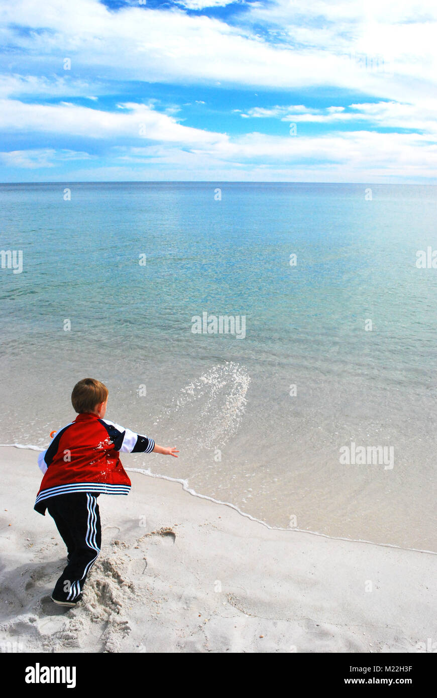 A young boy throw sand back into the ocean Stock Photo Alamy