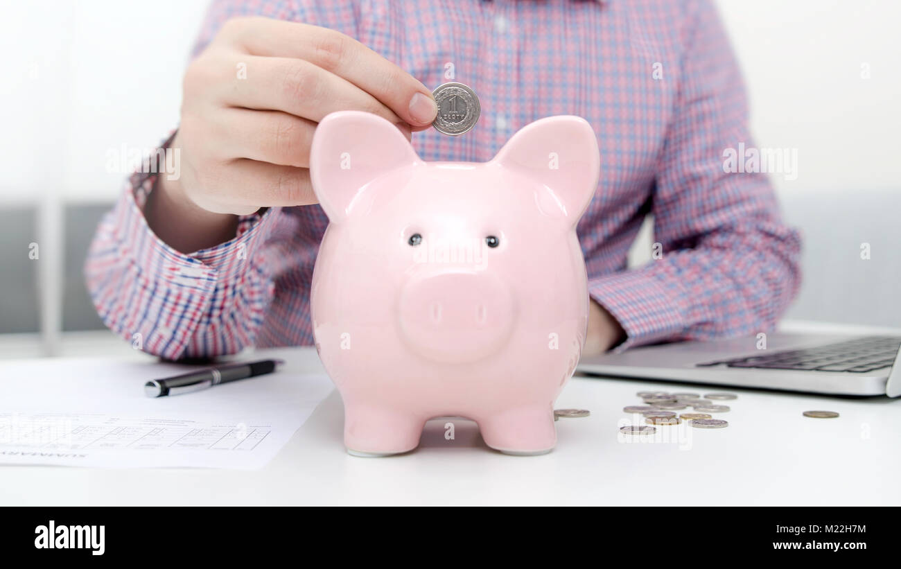 Man putting coin in piggy bank. saving money, budget, investment, finance concept Stock Photo