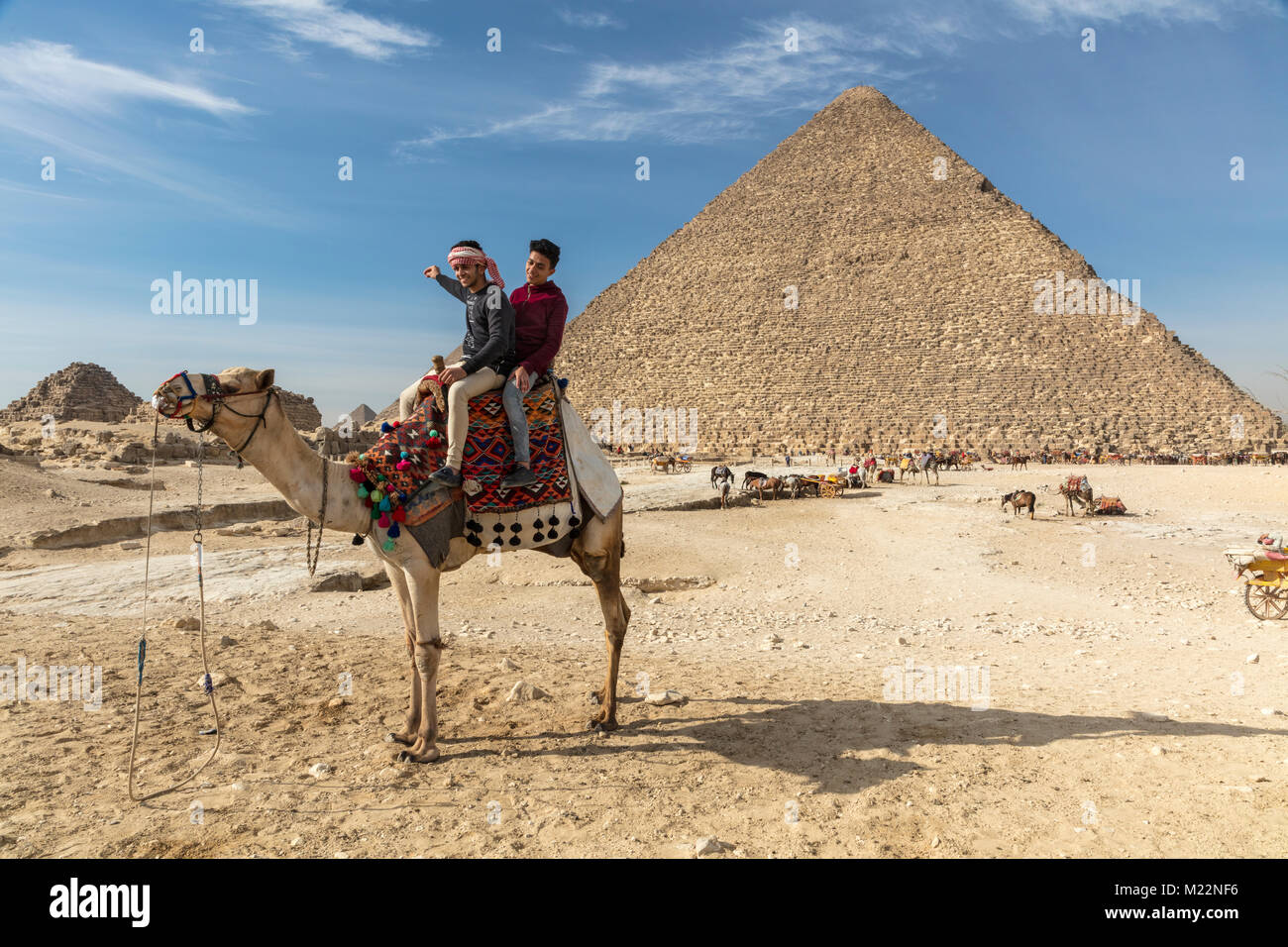Two Egyptian teens on a camel in front of the Great Pyramid of Khufu (Cheops) at Giza Stock Photo