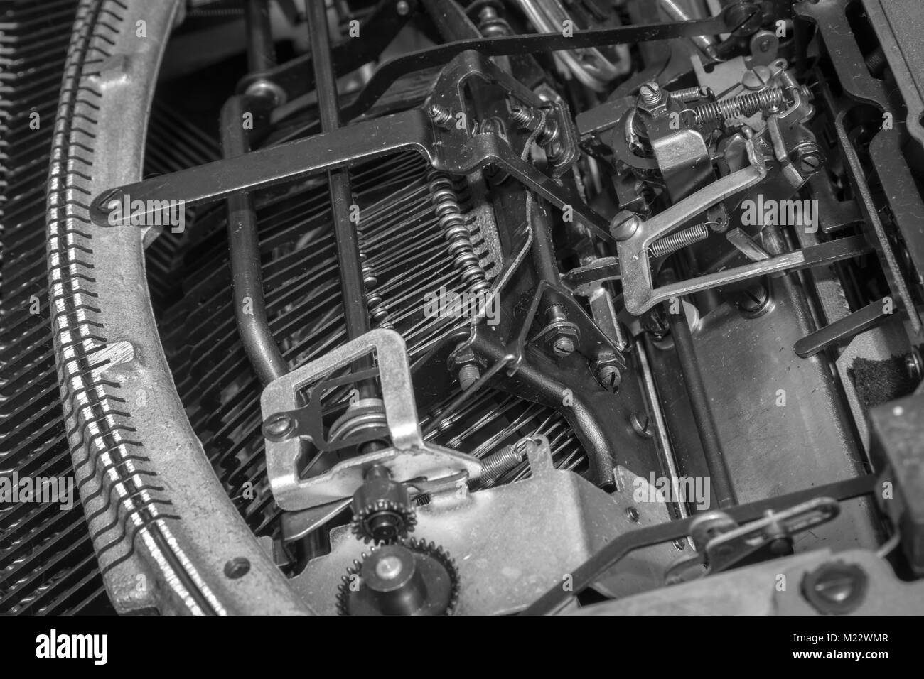 A view of an antique manual typewriter mechanism from underneath a portable typewriter built in the 1940s. Stock Photo