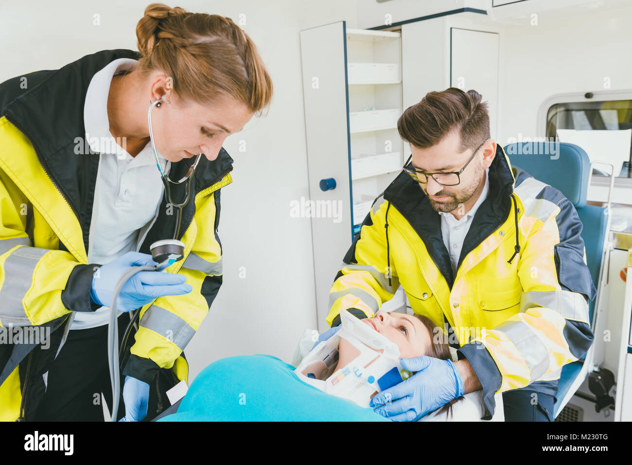 Medic taking care of injured woman with whiplash in ambulance Stock Photo