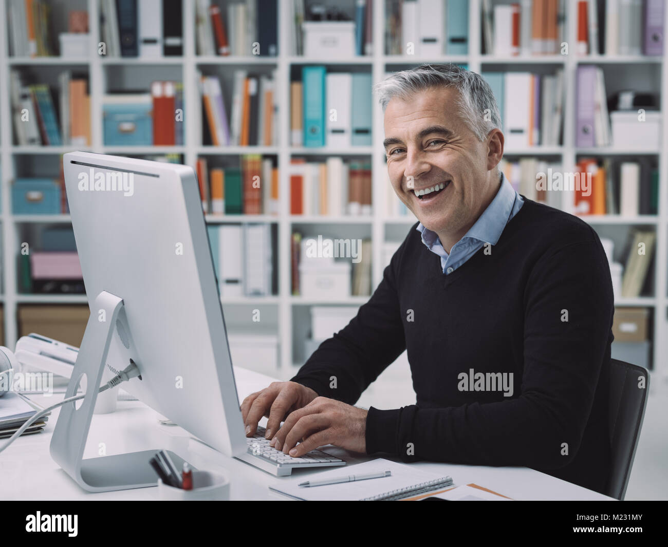 Confident Businessman Sitting At Desk And Working With His